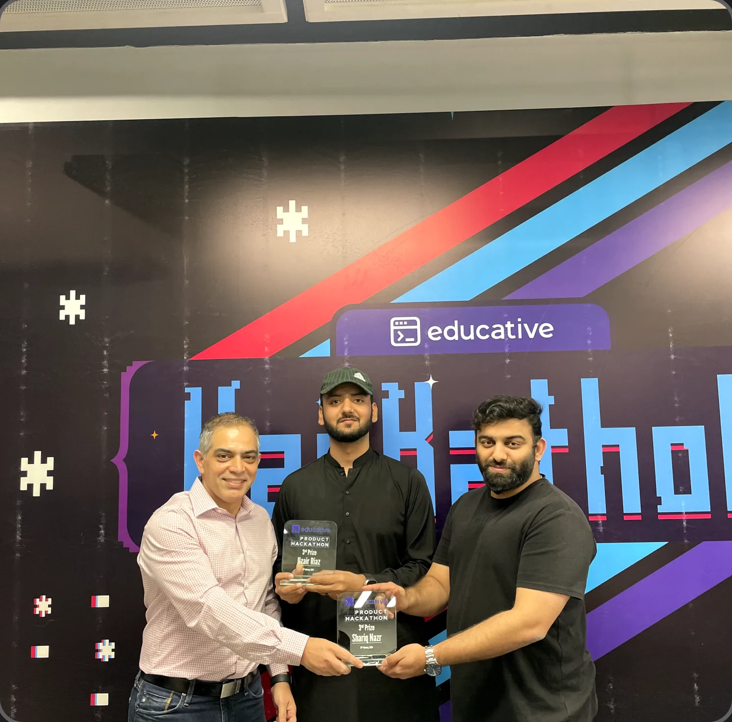 Uzair holding the Educative product hackathon trophy with two colleagues